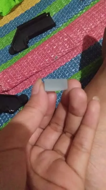 The small clear glass piece used as the reflector, held between two fingers