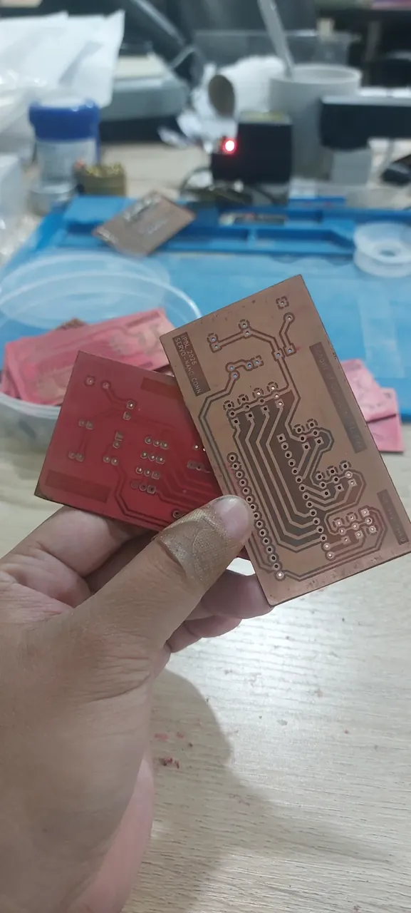Two hand-etched copper circuit boards held up in hand, one labeled iPBL 2026 Servo-Nano Conn, School of Computer Studies