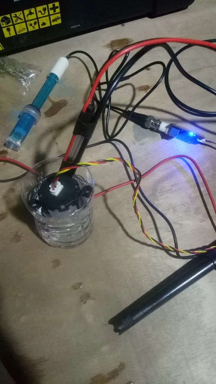 The probes under test: a turbidity sensor sitting in a cup of water, with the pH and conductivity probes beside it